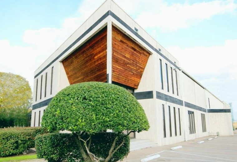 Exterior facade of the modern office building at 2800 Antoine Drive with wood paneling and manicured greenery.