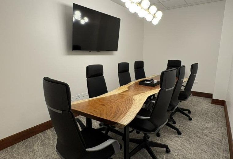 A wooden live-edge conference table and black leather chairs at 290, Avenida Jesús T. Piñero, GF 102.