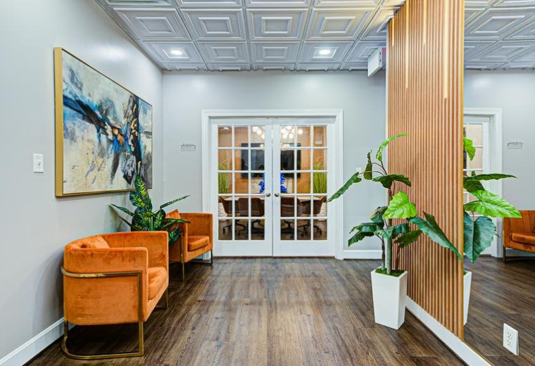 Bright office reception at 3240 Office Pointe Place featuring orange velvet armchairs and abstract artwork.
