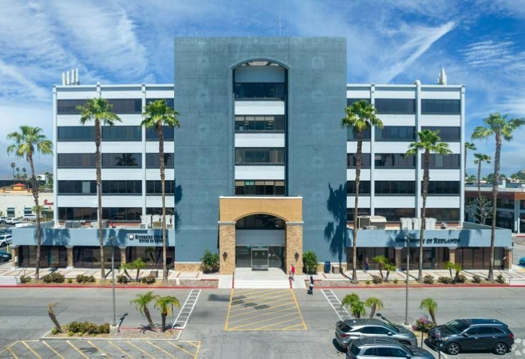 Exterior view of the office building at 3610 Central Avenue, Suite 400 with a blue facade and palm trees.