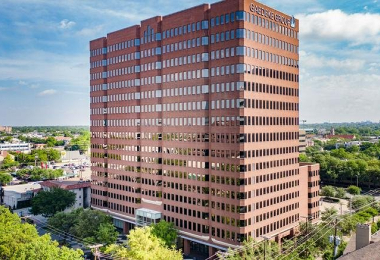 Full-height view of the brick office building exterior surrounded by greenery.