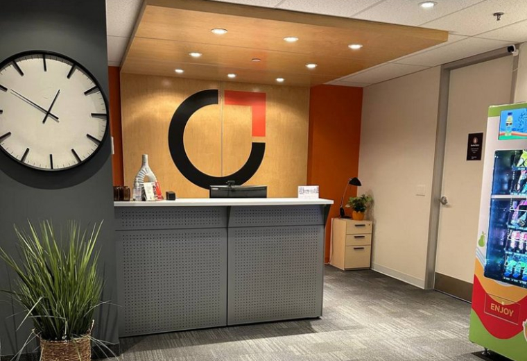 Modern reception area with a large circular logo, wooden canopy, and a digital snack kiosk at The Curators Hub.
