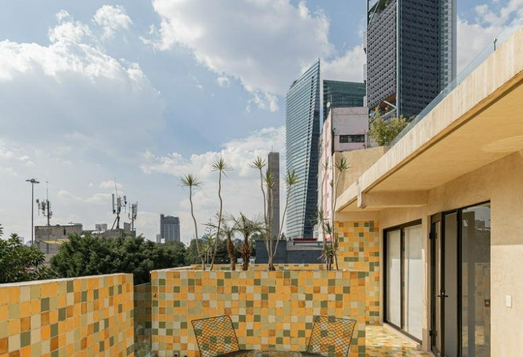 Outdoor terrace with vibrant yellow and green tiled flooring overlooking the city skyline.