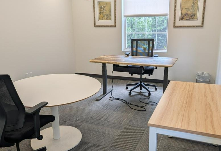Spacious private office with a round meeting table, two workstations, and ample natural light at 4301, 50th Street Northwest.