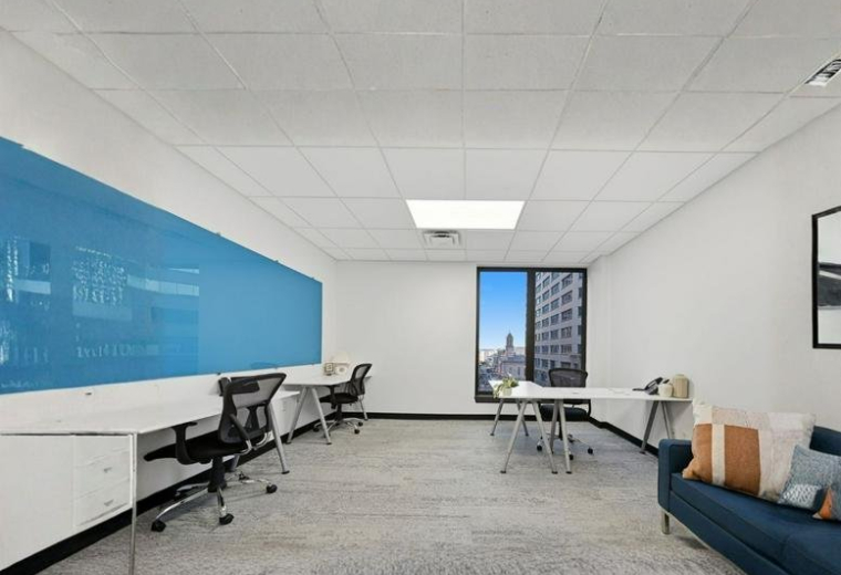 Bright open-plan workspace featuring a large blue whiteboard wall and blue sofa.