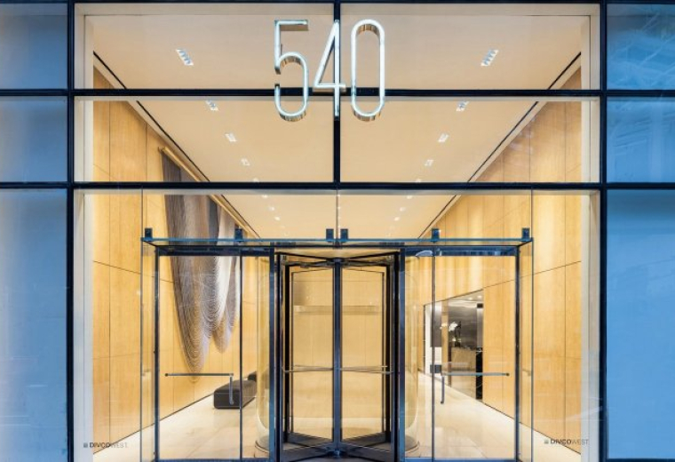 Modern glass entrance at 540 Madison Avenue featuring a revolving door and illuminated building number.