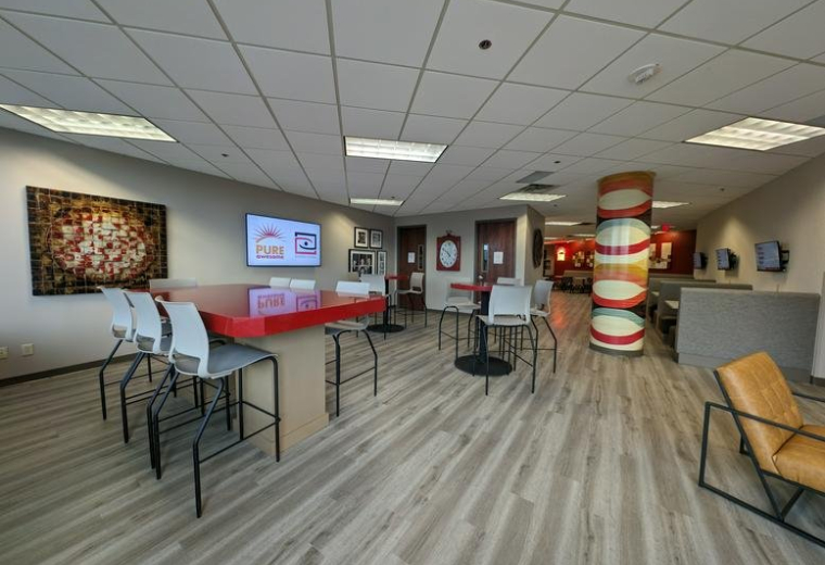 Spacious communal lounge at 7900 International Drive featuring a red high-top table and colorful striped pillar.