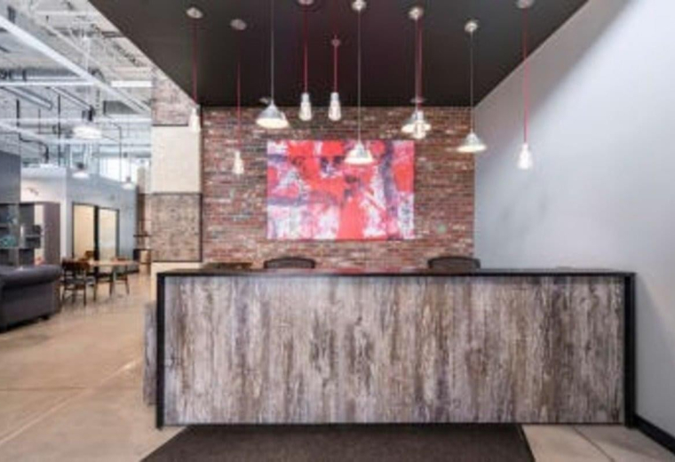 Modern reception at Keele Rutherford Corporate Centre featuring a rustic wood desk and red feature wall art.