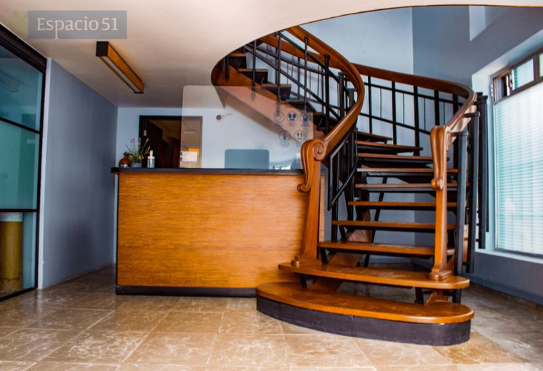 Reception area at Av Tres num 51, Col. San Pedro de los Pinos with a wooden desk and elegant spiral staircase.