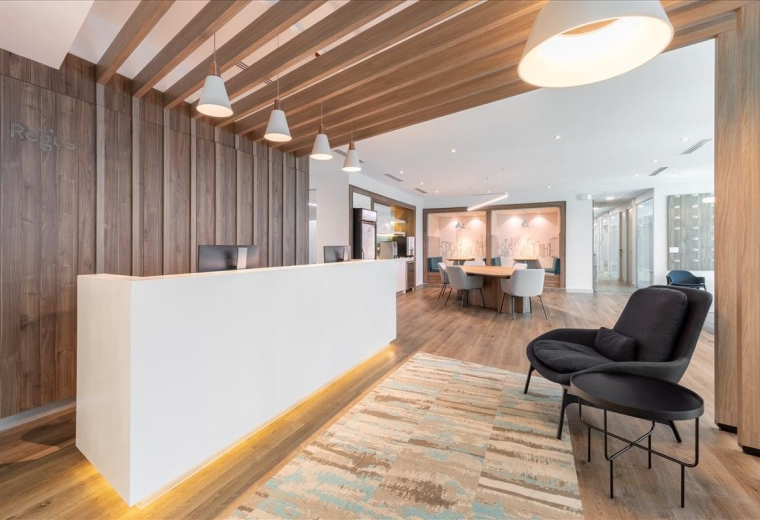 Minimalist reception area with a white desk, wooden slat wall, and pendant lighting.