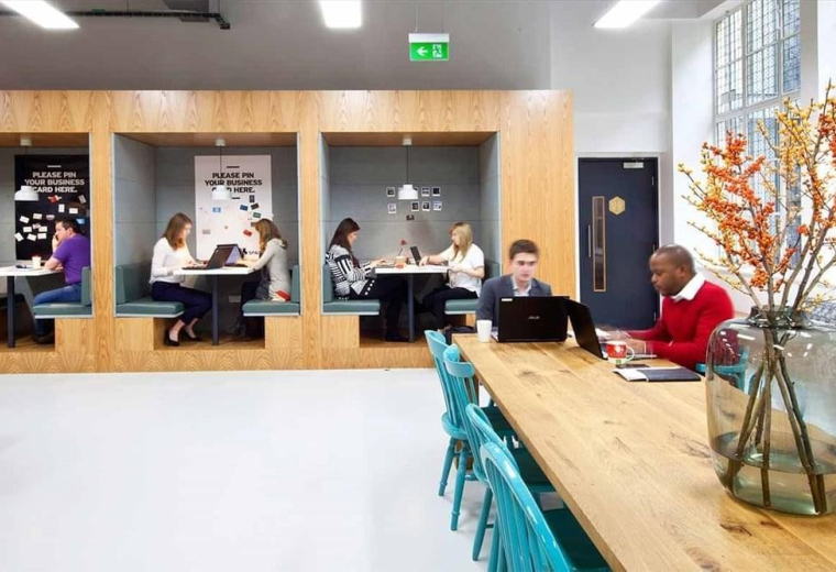 Modern coworking space at Plaza 2000 featuring private wooden booths and a long communal table.