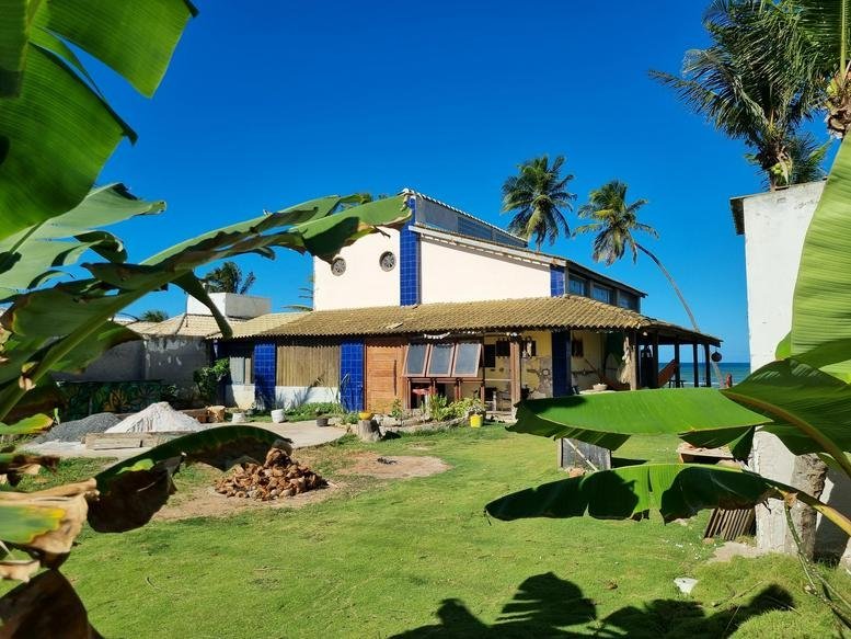 Exterior view of the white and blue building at 07, Rua Aquárius, Casa 218, with palm trees.