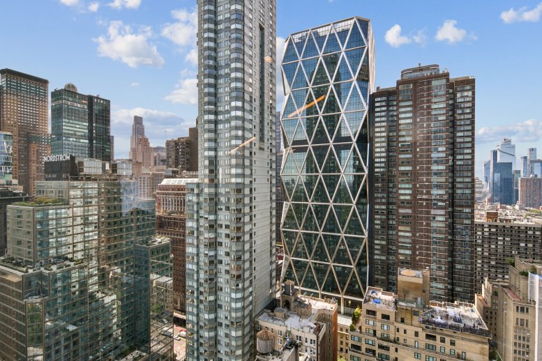 Exterior view of the glass and steel architecture of 1 Columbus Circle surrounded by Manhattan skyscrapers.