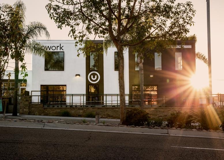 The modern white and black facade of Union Cowork at 111, C Street during a bright sunset.