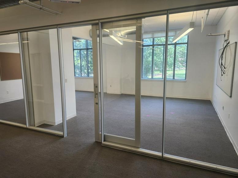 Private glass-walled office at 1226 Olive Street with natural light and view of greenery.