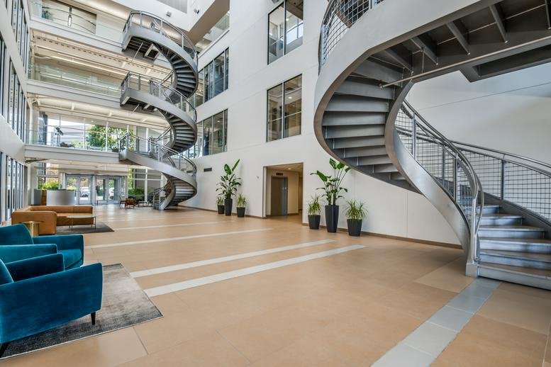 Spacious, modern lobby at 130, East John W Carpenter Freeway, Suite 220 featuring dramatic spiral staircases and plants.