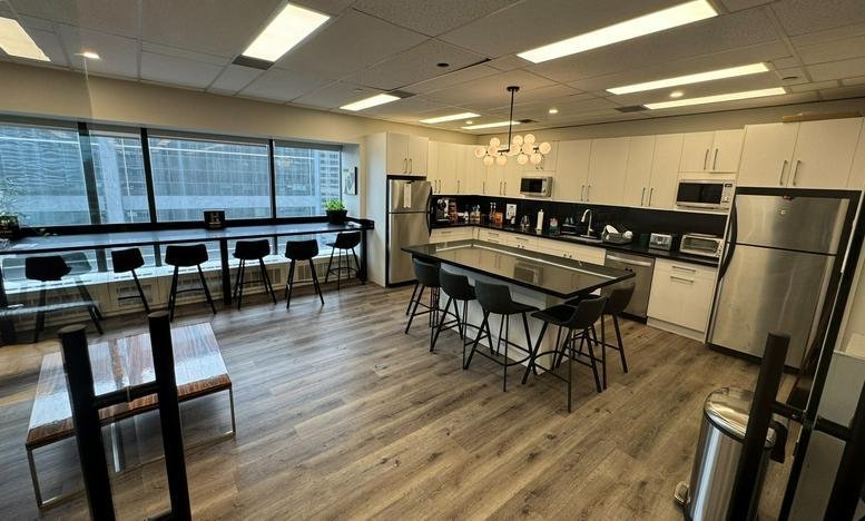 Modern kitchen and communal dining area with stainless steel appliances and breakfast bar.