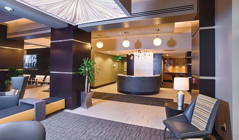 Modern building lobby featuring a sleek reception desk, warm lighting, and contemporary seating areas.