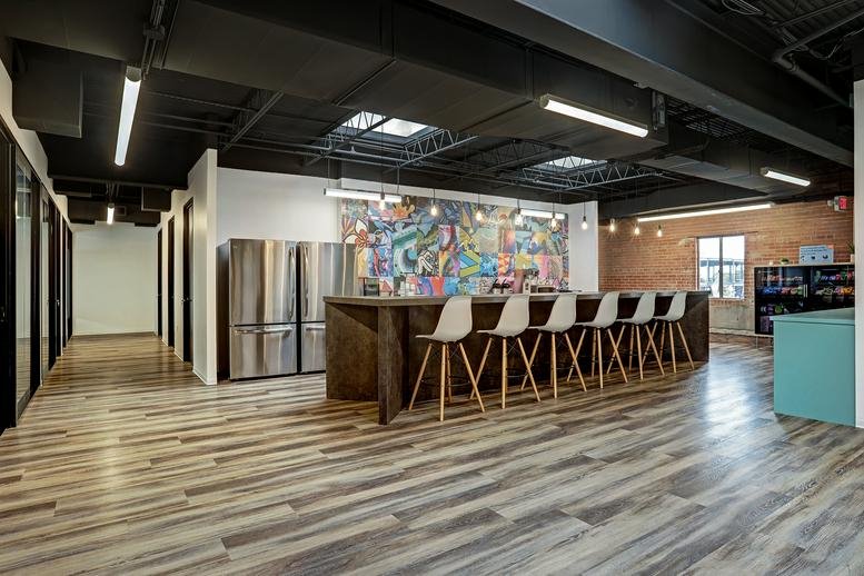 Spacious communal break area at 1923, Washington Avenue with wood floors and a colorful mural.