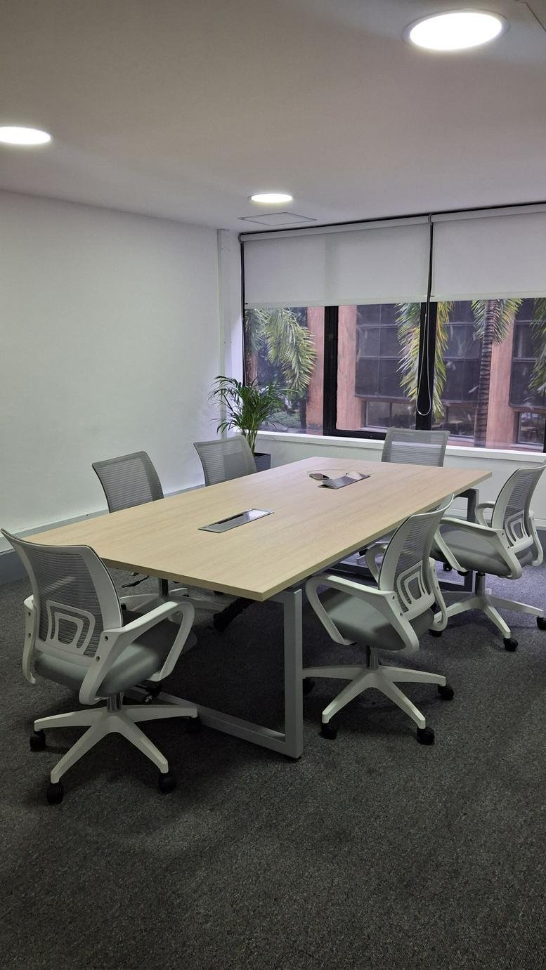 Spacious boardroom at 1a Sur-69, Carrera 43A with a light wood table and modern grey mesh chairs.