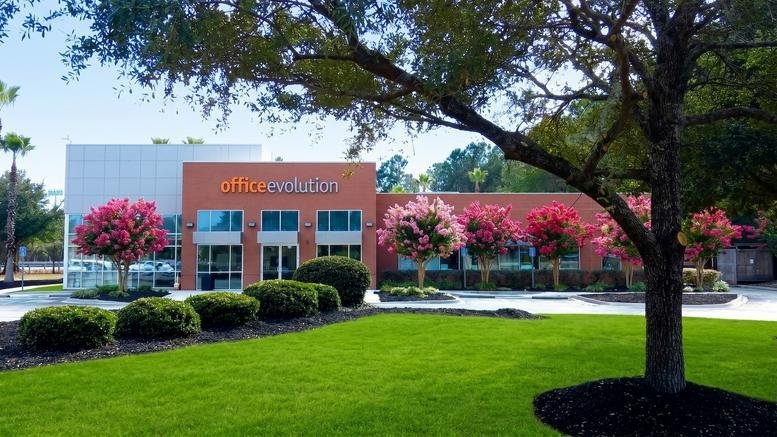 Exterior view of the Office Evolution building at 20 Martin Court with pink flowering trees and green lawn.