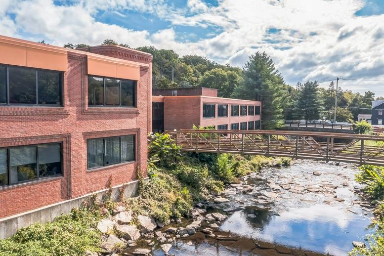 Exterior view of the brick office building at 200 Pemberwick Road alongside a scenic river.
