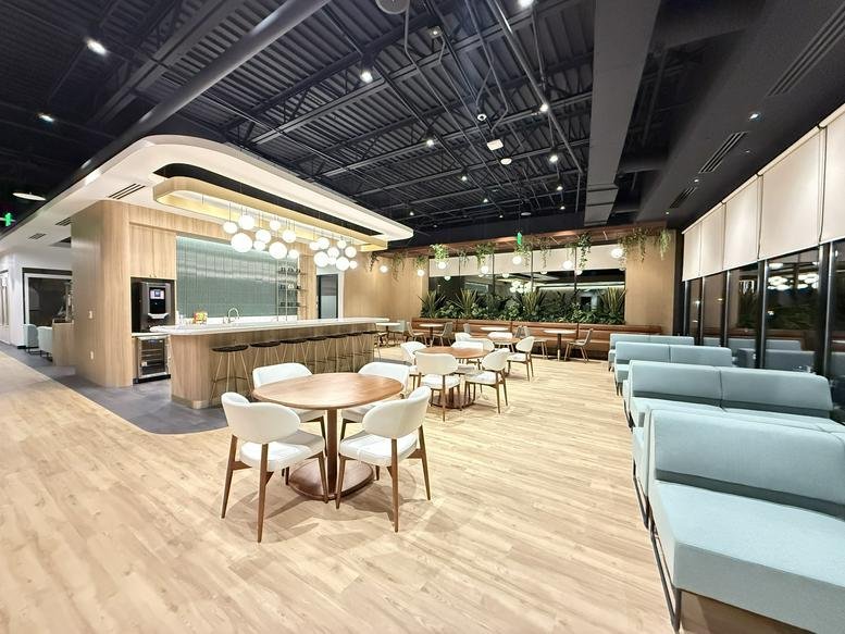 Spacious communal lounge and cafe area with wood floors, blue seating, and a modern bar at 23710, Schooler Plaza.