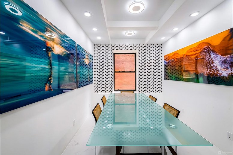 Meeting room at 245, 8th Avenue with a glass table, patterned wallpaper, and large colorful abstract wall art.
