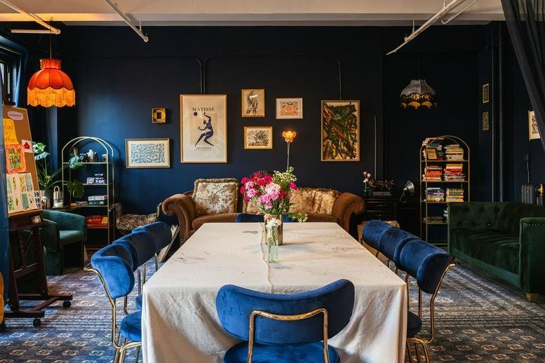 Meeting room at 247, West 30th Street, 9R with navy blue walls, vintage artwork, and a long white-clothed table.