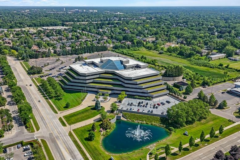 Wide aerial view of the building facade and landscaped pond with a fountain.