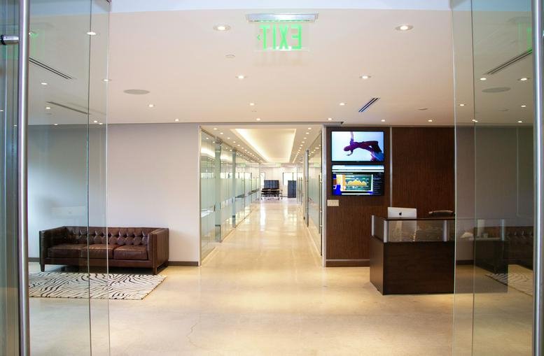 Modern reception area with a dark wood desk and comfortable leather sofa.