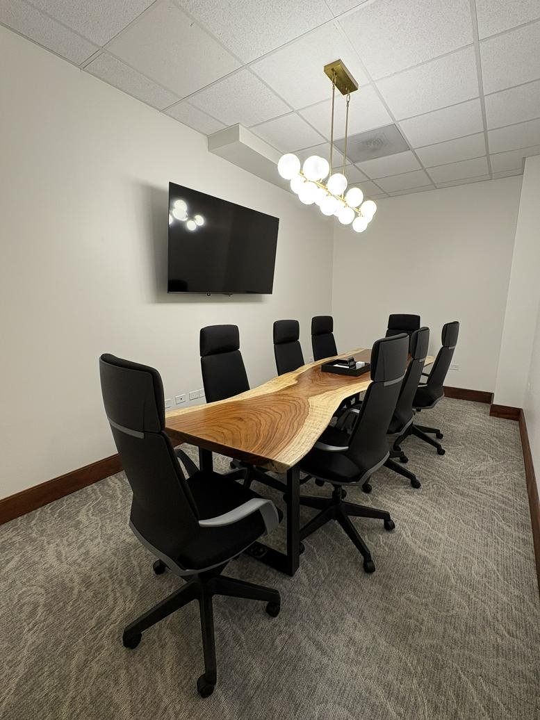 A wooden live-edge conference table and black leather chairs at 290, Avenida Jesús T. Piñero, GF 102.