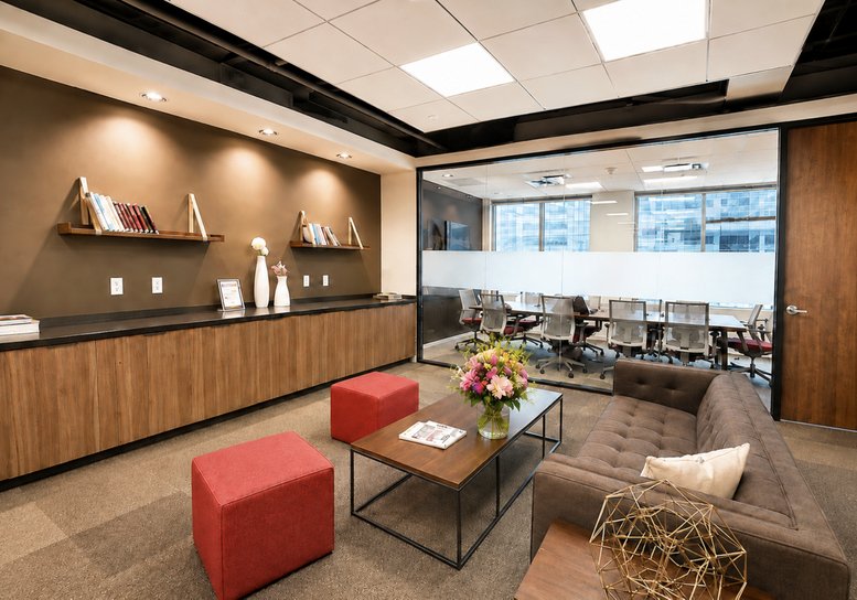 Contemporary lounge area with red ottomans, brown sofa, and a glass-walled meeting room.