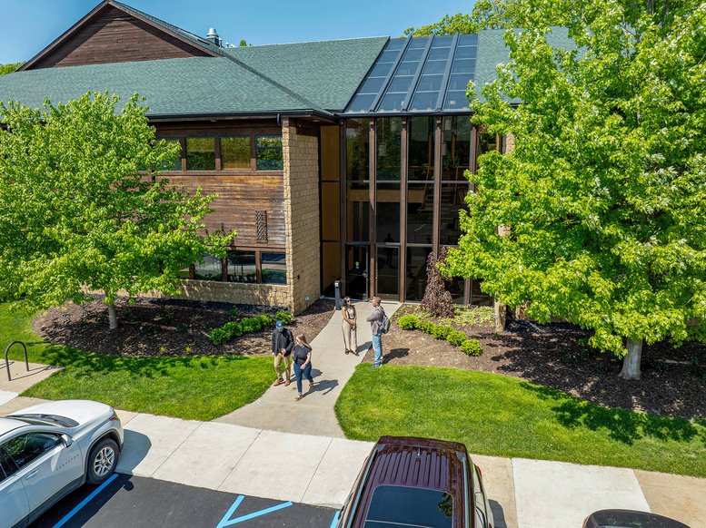 Exterior view of the wood and glass building at 3027 Miller Road featuring lush green trees.