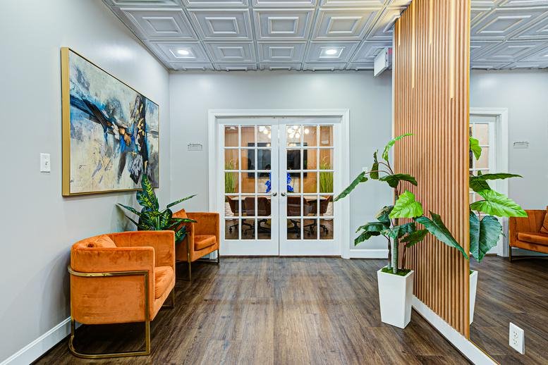 Bright office reception at 3240 Office Pointe Place featuring orange velvet armchairs and abstract artwork.