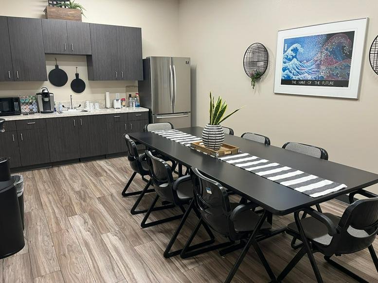 Modern communal kitchen and dining area at 3730, West Swift Avenue with a long table and dark cabinetry.