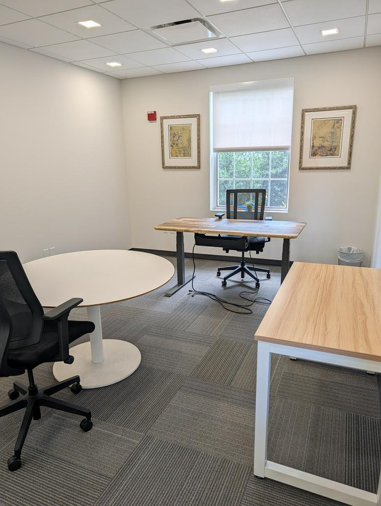 Spacious private office with a round meeting table, two workstations, and ample natural light at 4301, 50th Street Northwest.
