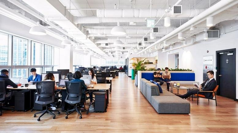 Bright, high-ceilinged open-plan workspace at 438, King Street West featuring desks and lounge areas.