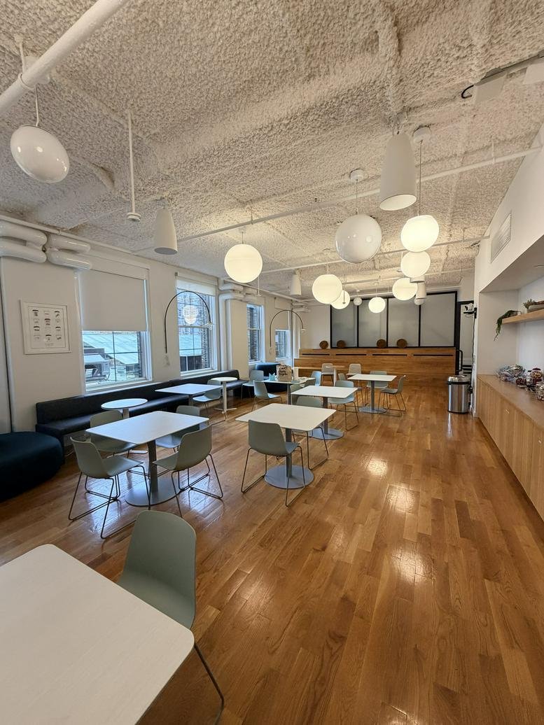 Spacious communal cafe area at 44 West 18th Street with wooden floors and globe lighting.