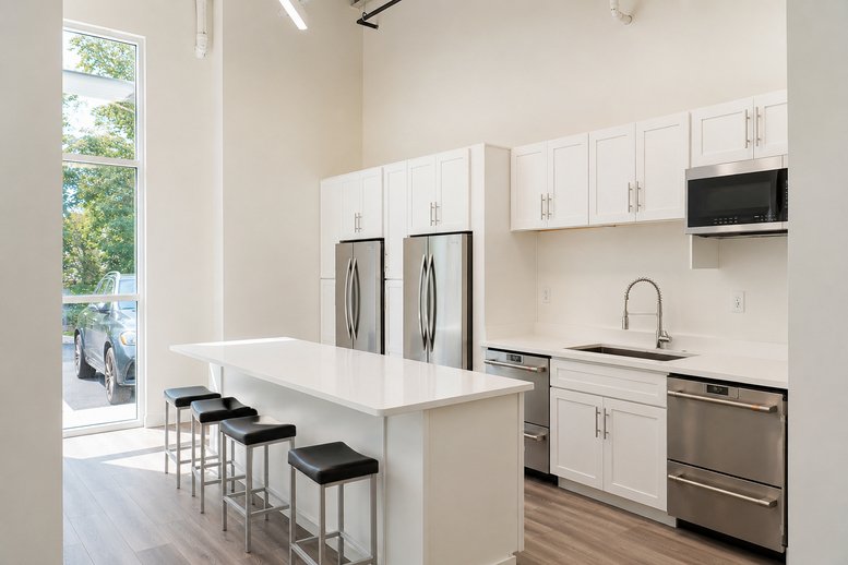 Modern communal kitchen at 4416 Expressway Drive with white cabinetry, marble island, and stainless appliances.