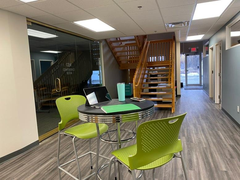 Spacious communal lounge at 45, Industrial Road, Suite 100 with green chairs and wooden stairs.