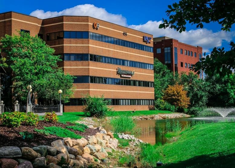 Lush exterior view of the office building beside a scenic pond and fountain.