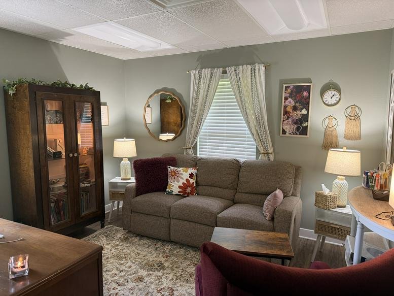 Reception area at 5002, Lotus Lane with a comfortable sofa, warm lighting, and a dark wood cabinet.