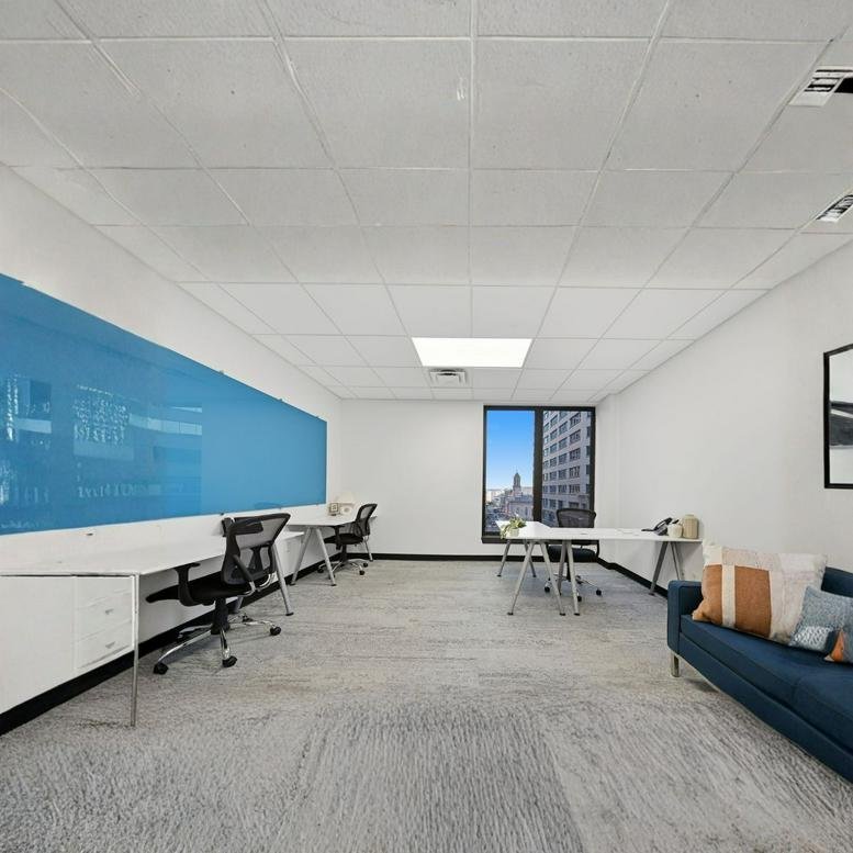 Bright open-plan workspace featuring a large blue whiteboard wall and blue sofa.
