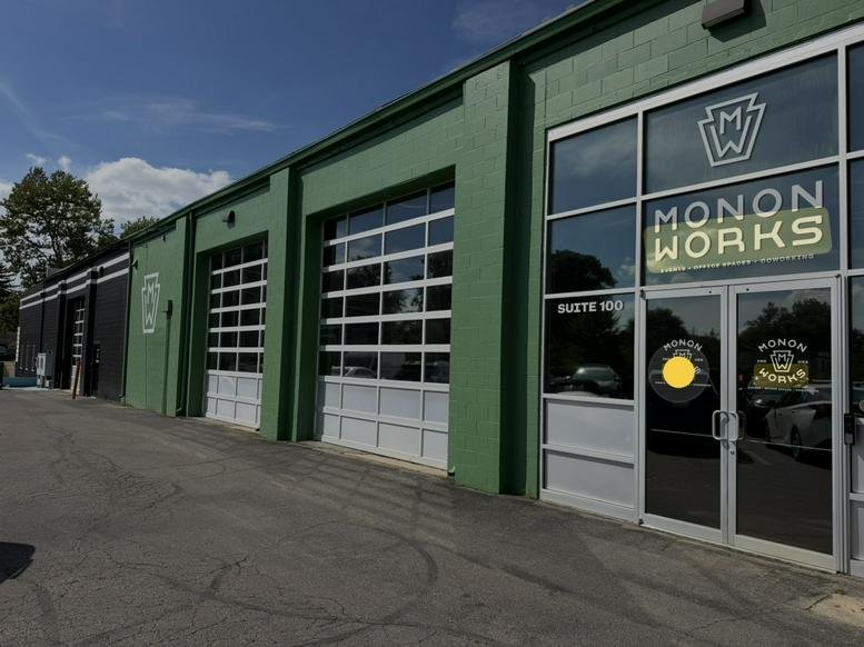 Main entrance of the green building with large glass doors and signage.