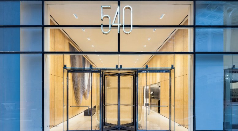 Modern glass entrance at 540 Madison Avenue featuring a revolving door and illuminated building number.