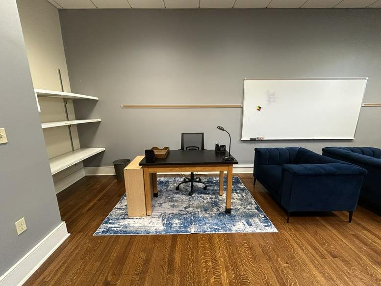 Private office at 6227, Saint Charles Avenue featuring wood floors, blue armchairs, and a white shelving unit.
