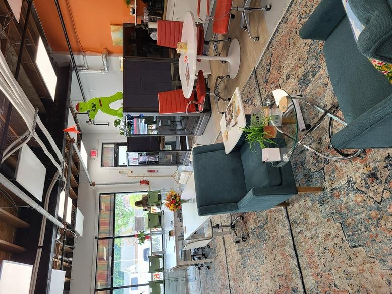 Colorful open-plan workspace at 6769, Main Street with lounge seating and bright orange accents.
