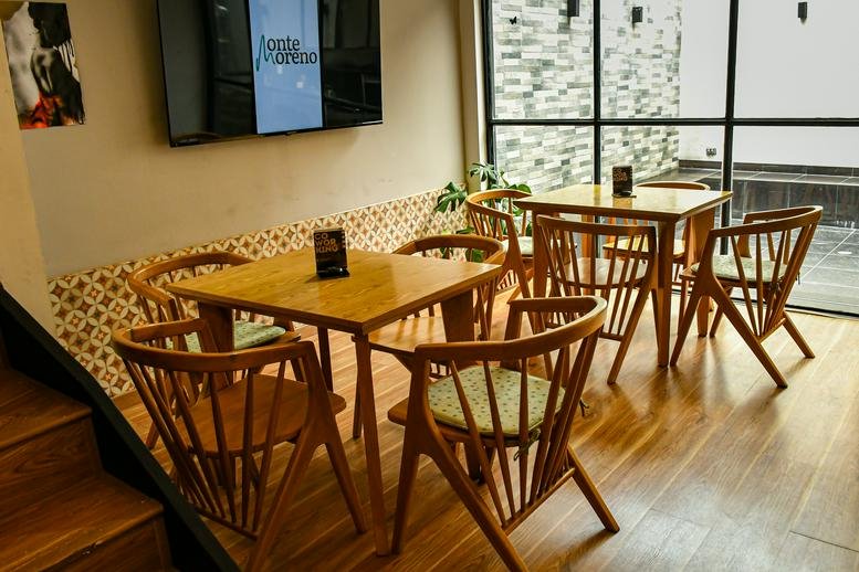 Sunny cafe-style breakout space at 73-56, Carrera 20c with wooden tables and chairs.
