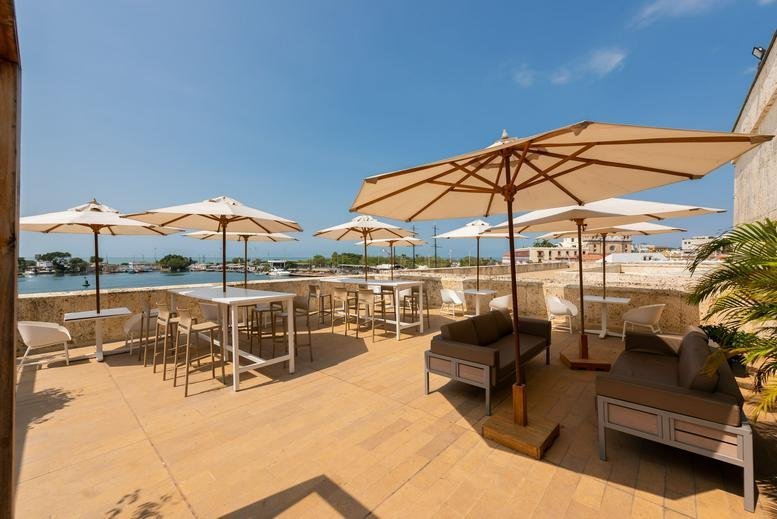 Sun-drenched rooftop terrace at 8A-344, Calle 24 with umbrellas, lounge seating, and water views.